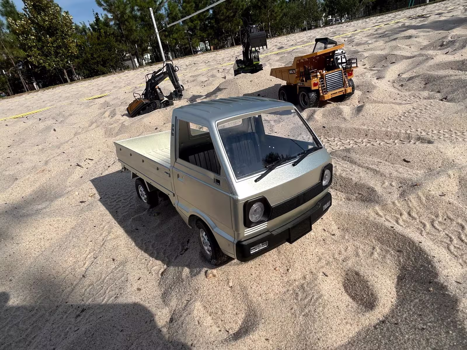 A fleet of realistic scale RC excavators and dump trucks digging through a sand construction site.
