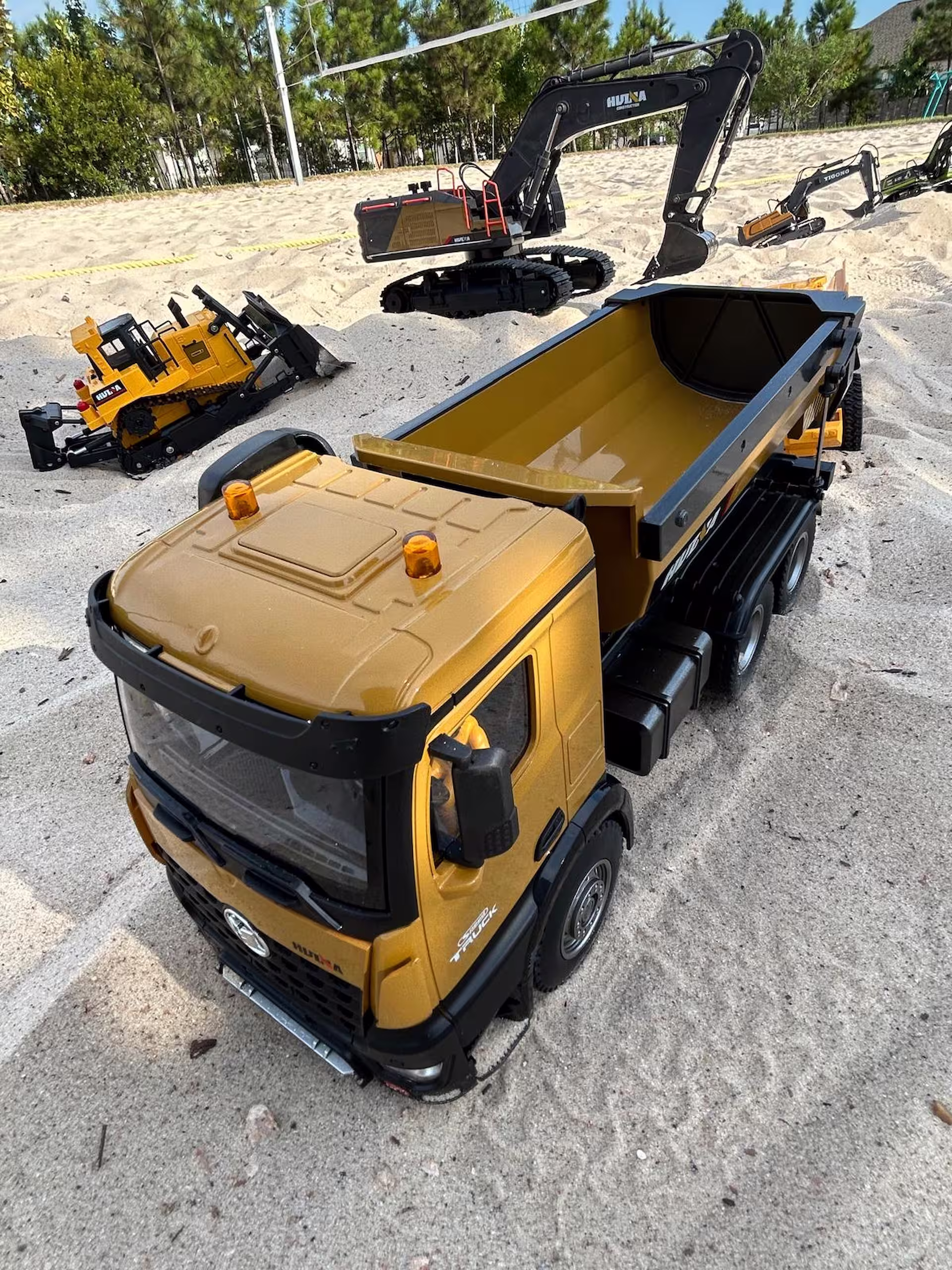 Miniature excavator and dump truck in action on a sandy construction site